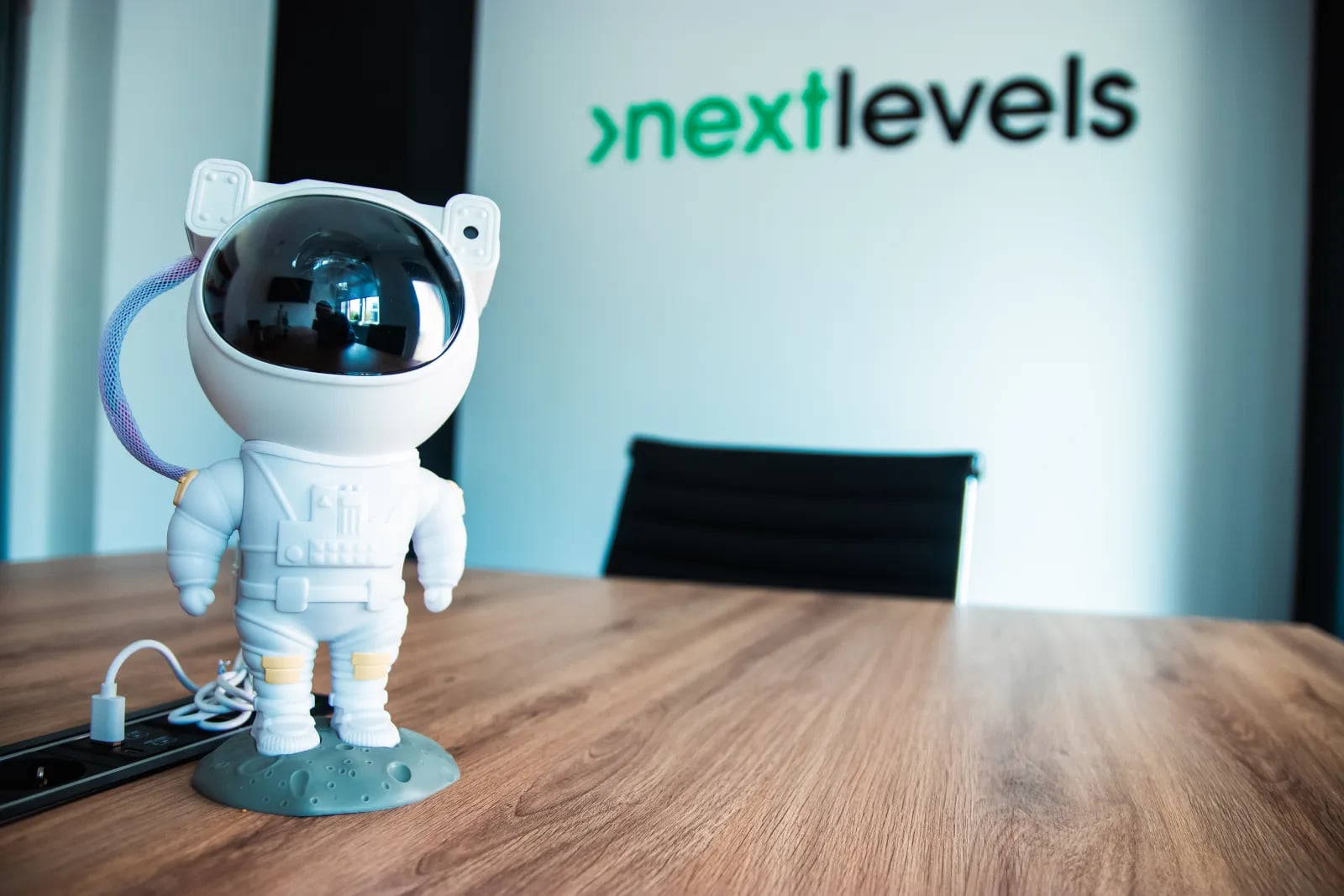 Astronauten-Figur auf dem Konferenztisch im nextlevels-Büro vor dem nextlevels-Logo