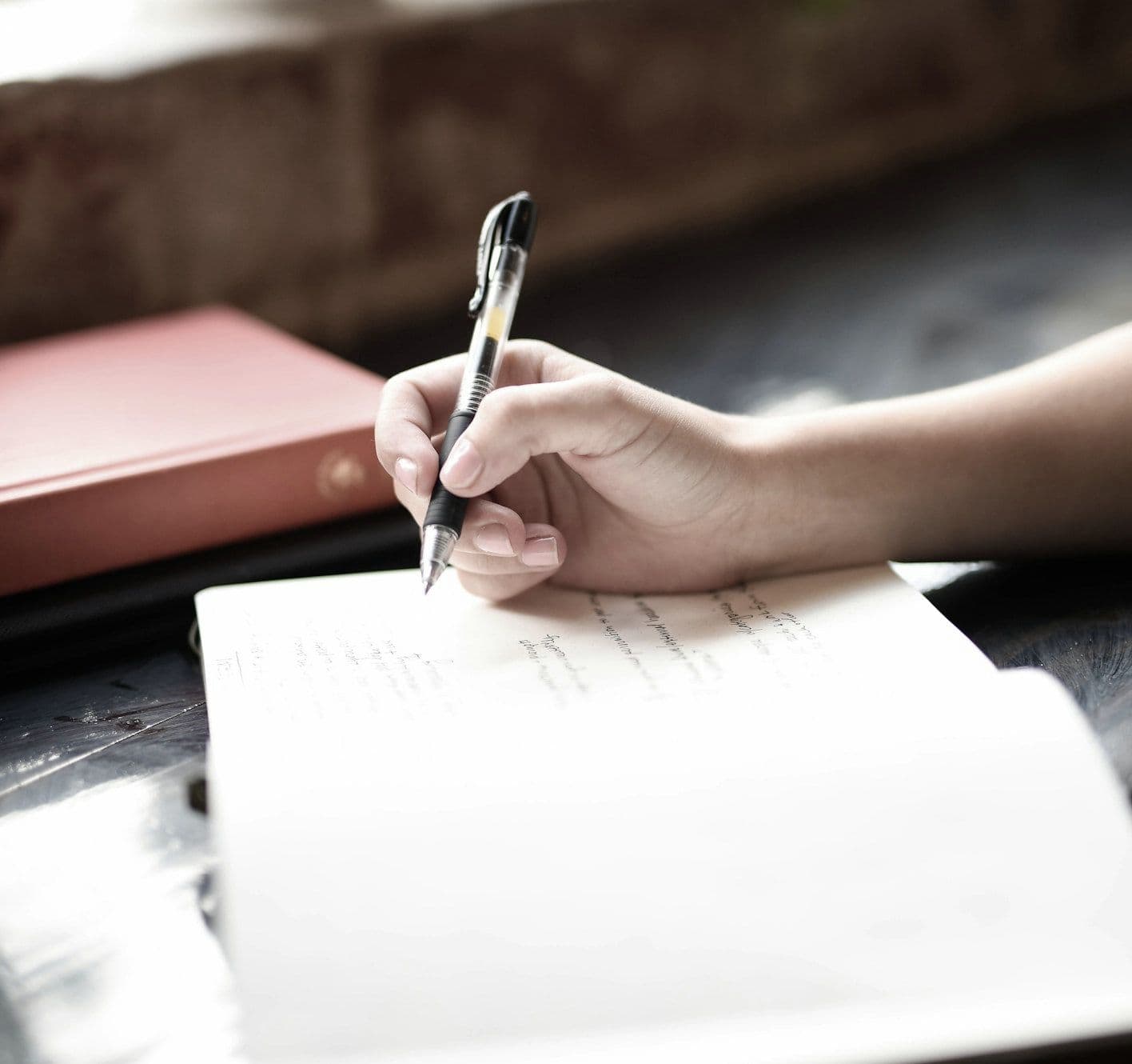 Hand writing with a pen in a notebook on a table Hand writing with a pen in a notebook on a table