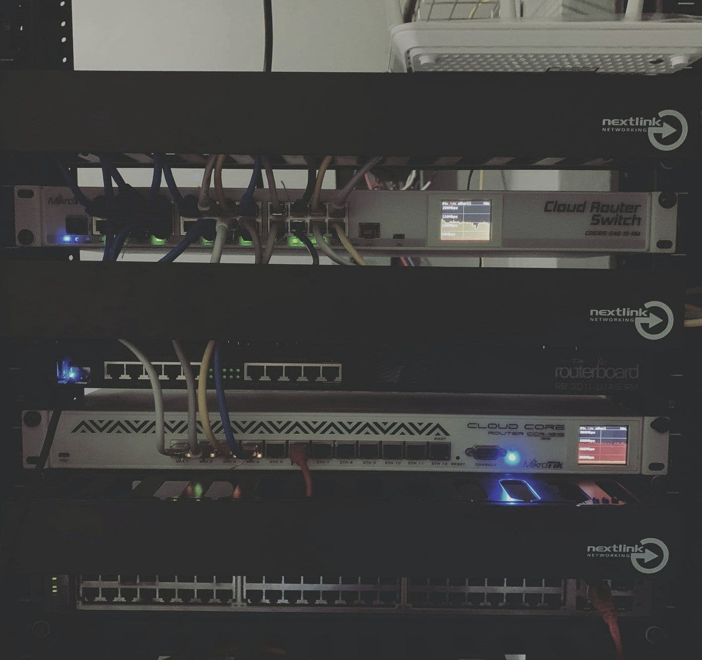 Small server rack with network devices and cables in a dark room Small server rack with network devices and cables in a dark room