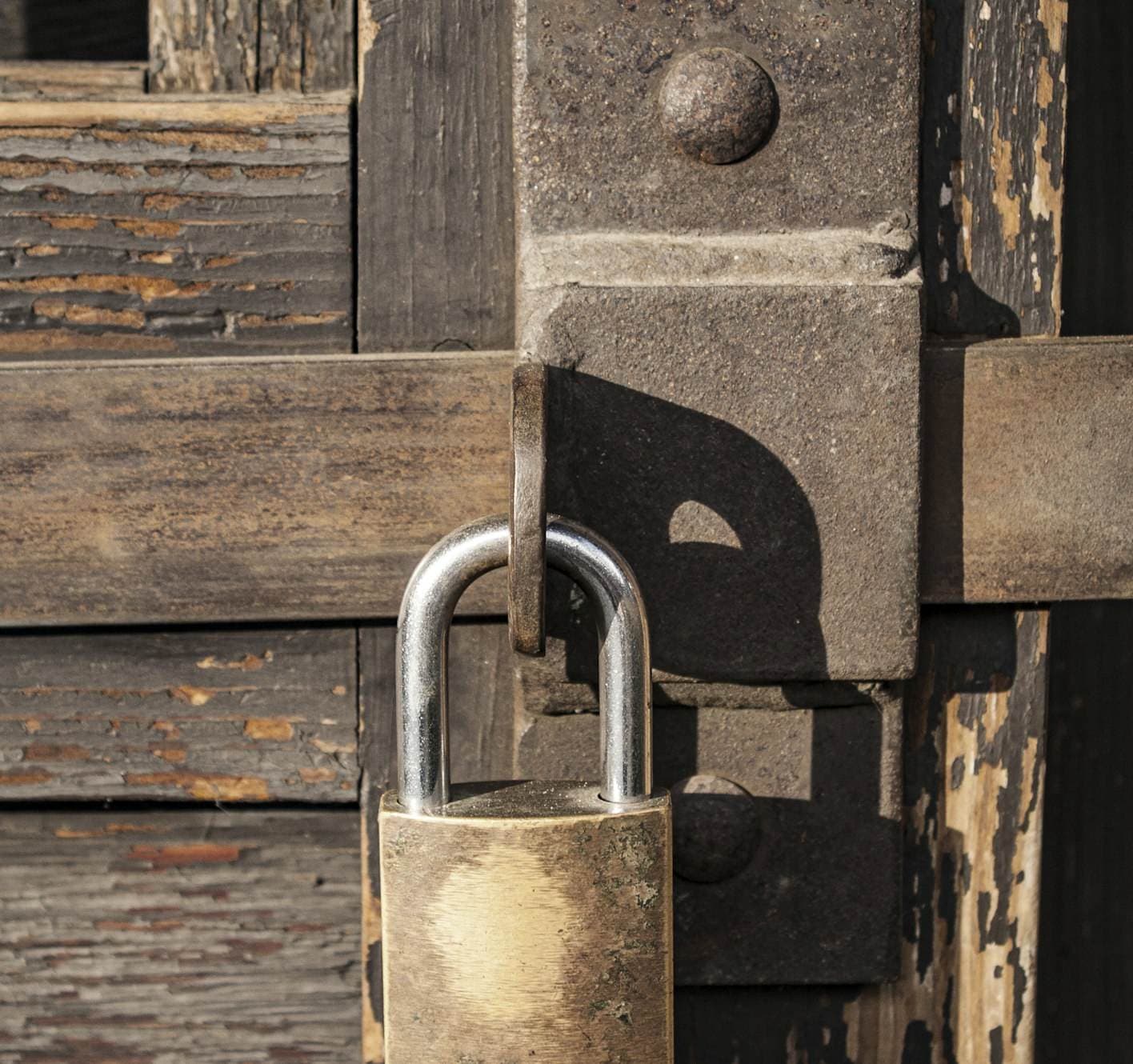 Padlock on an old wooden door with a latch Padlock on an old wooden door with a latch