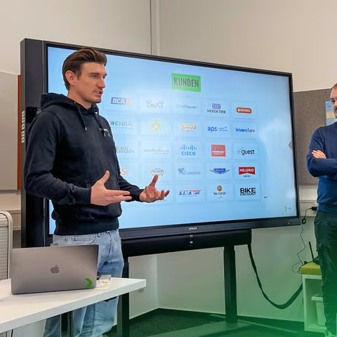 Präsentation bei nextlevels vor einem Bildschirm mit Kundenlogos