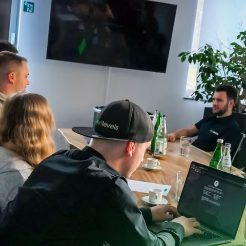 Team von nextlevels bei einer Besprechung mit Laptop und Bildschirm